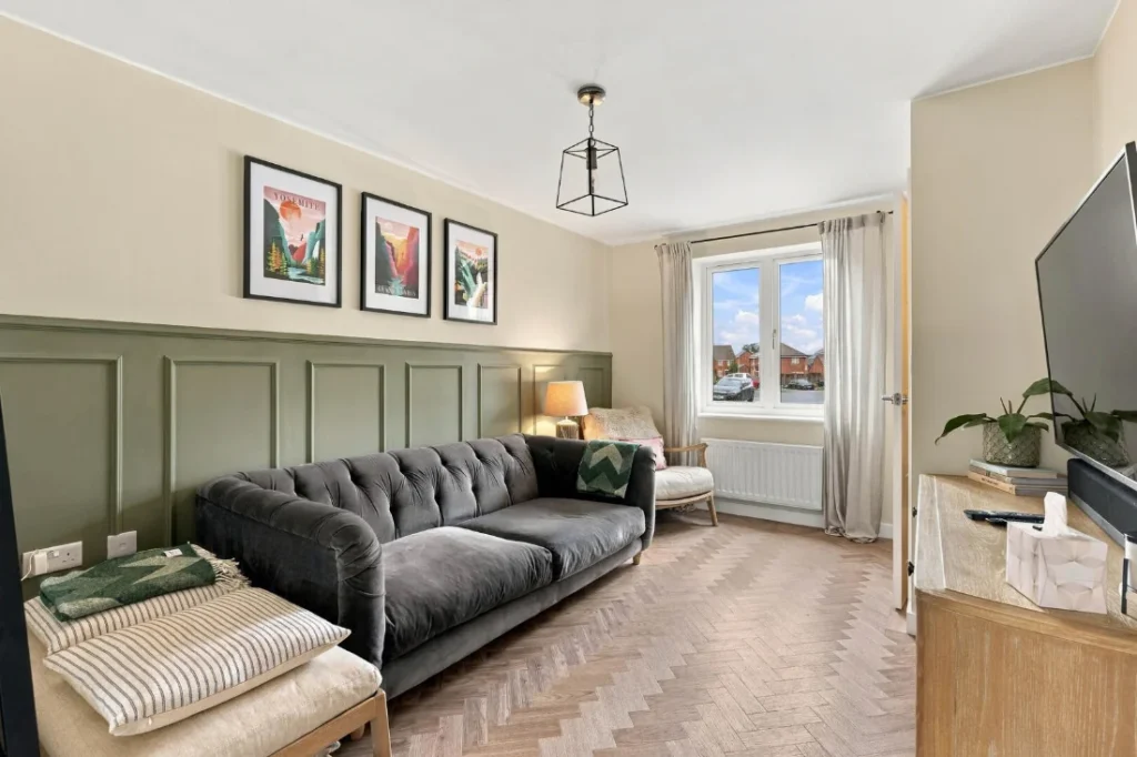 Living room with a grey velvet sofa and green panelling